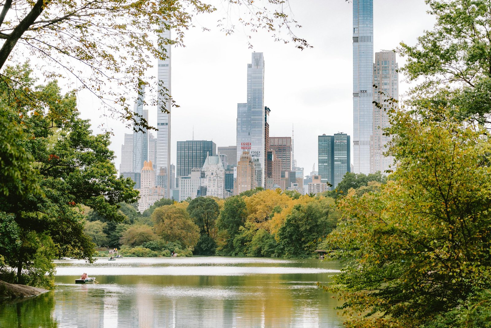 A tranquil view of Central Park lake with towering skyscrapers of New York City in the background.