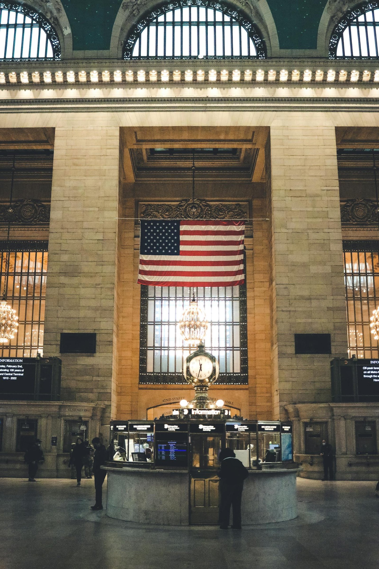 Inside view of Grand Central Terminal with American flag prominently displayed, showcasing iconic architecture.